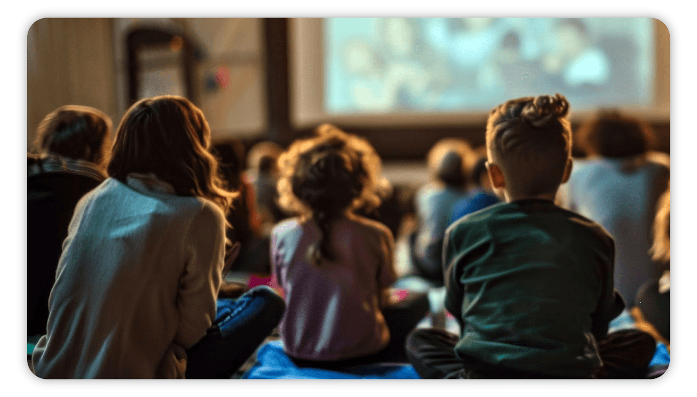 Children sitting together on the floor of a church hall watching a film on a projector screen